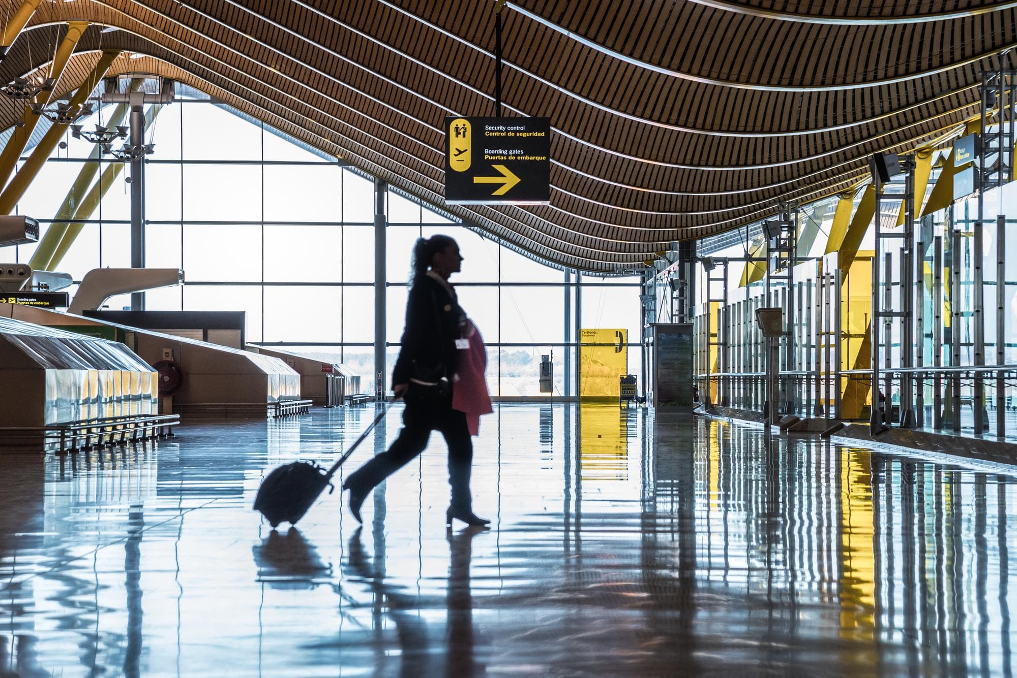 A traveller wheeling a suitcase through an airport terminal