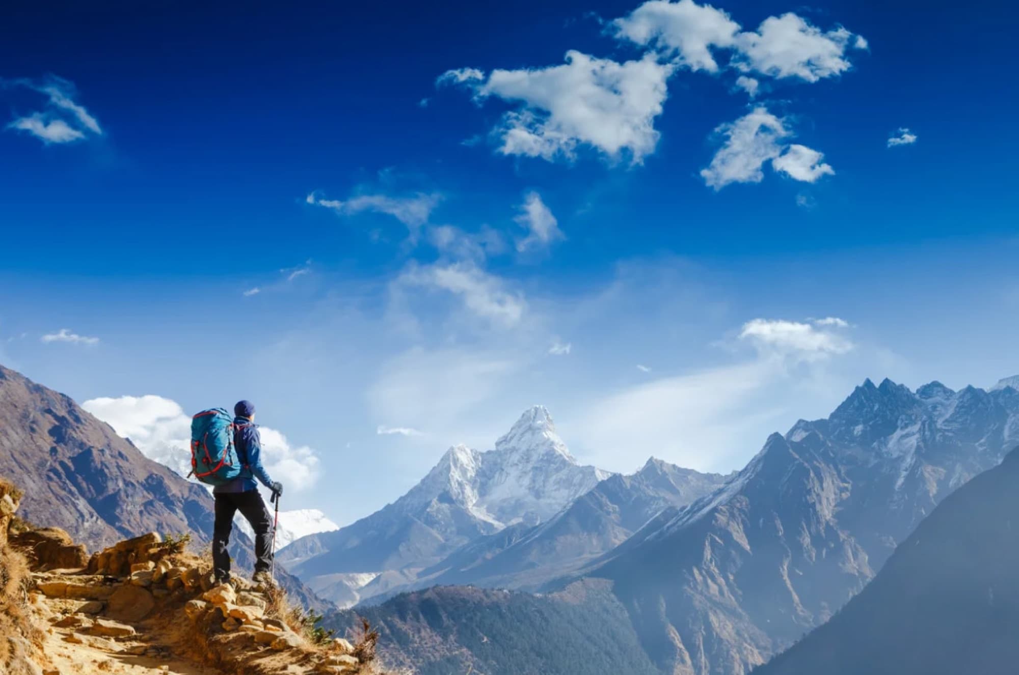 A hiker looking out over snow-capped mountains